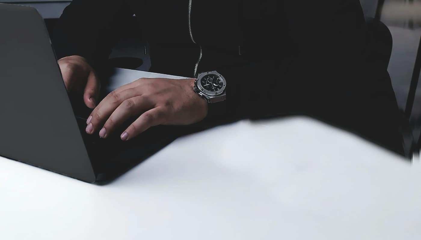 Hands typing on a laptop, with a watch on the wrist