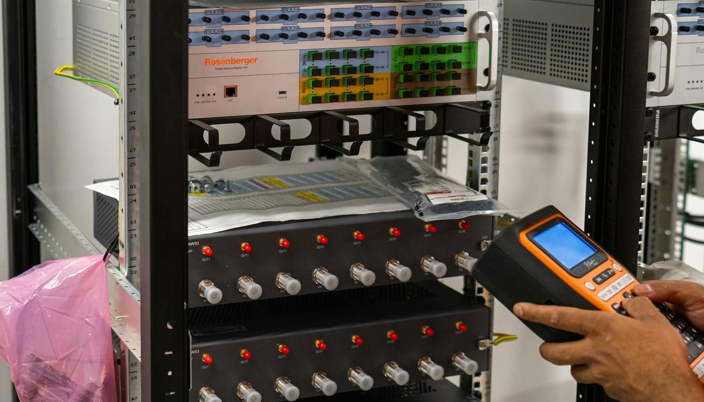 A technician holding a handheld tester at a server rack