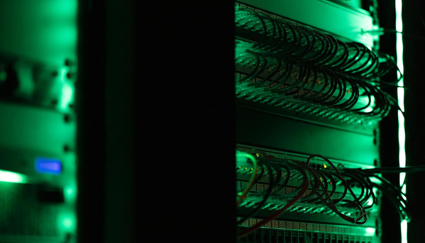 Green-lit cables and equipment in a dark server room