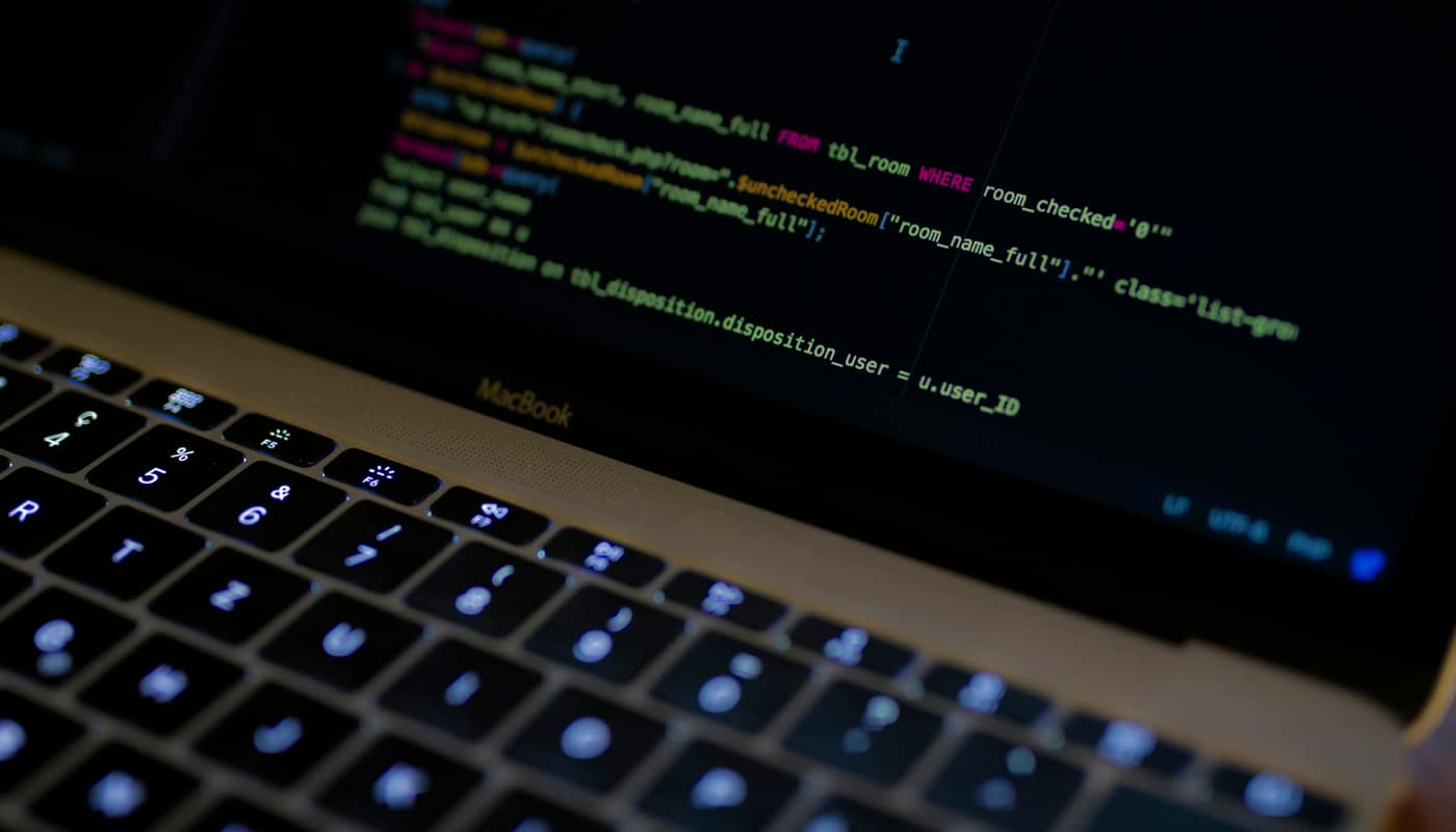 Lines of code on a laptop screen above a backlit keyboard